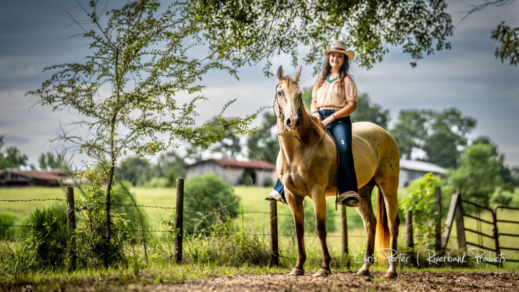 Cowgirl riding white horse next to fence